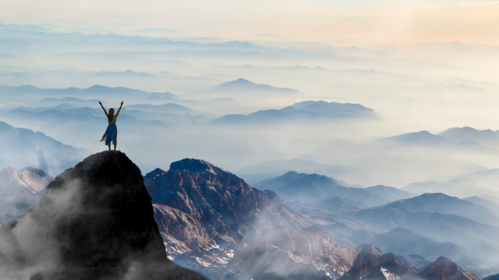 Achieving financial freedom. A man celebrating on top of a mountain